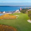 Aerial view of the 18th hole at Harbour Town Golf Links, featuring the closing fairway along the Calibogue Sound with the iconic red-and-white lighthouse in the background.