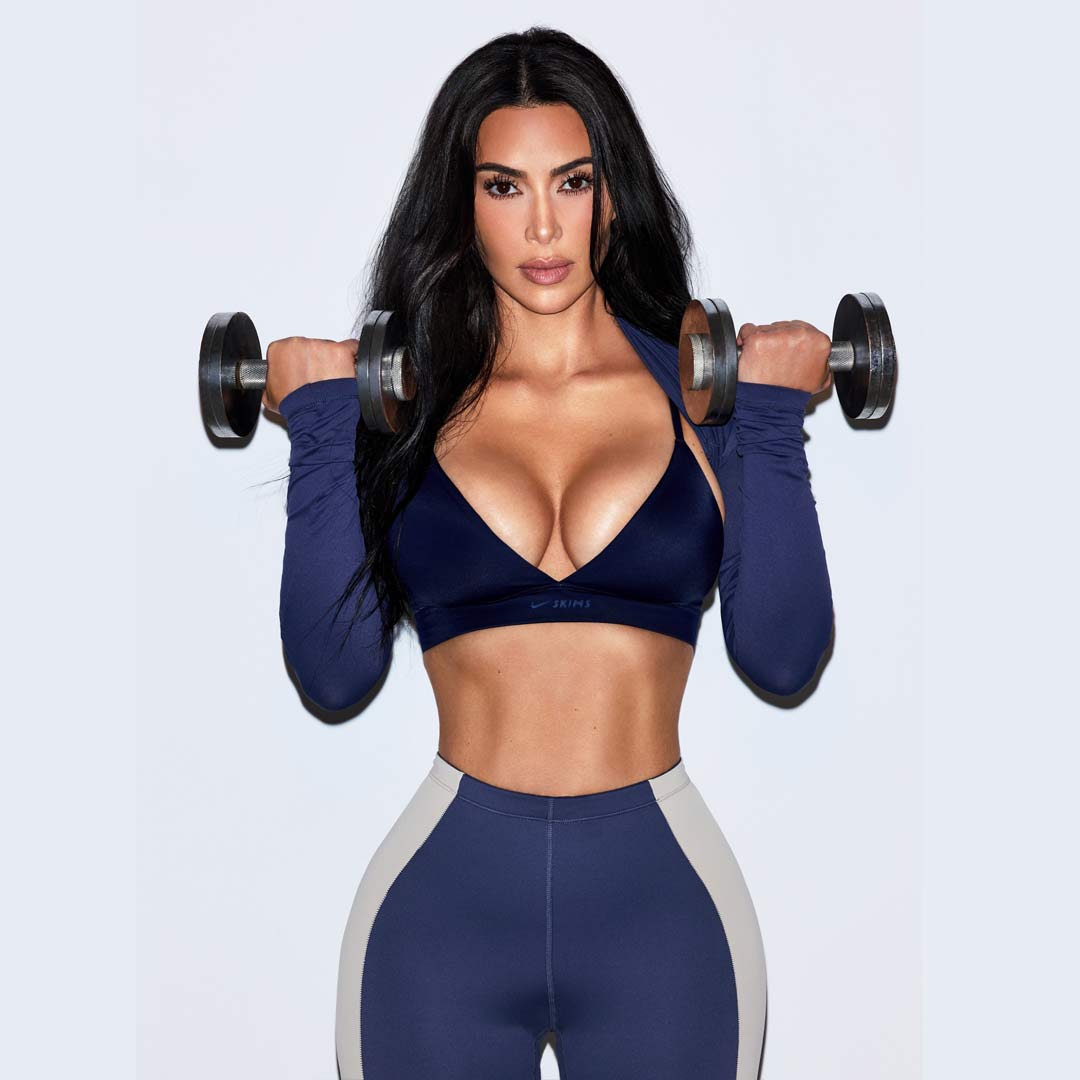 Kim Kardashian wears a NikeSKIMS navy bodysuit lifting weights
