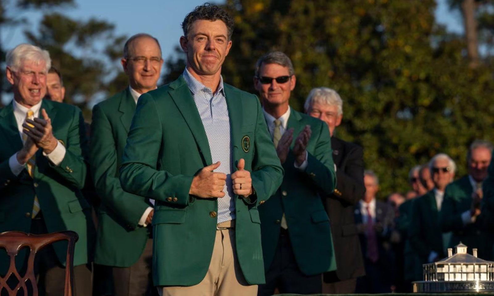 Rory McIlroy wearing the green jacket during the 2026 Masters champion ceremony at Augusta National, with officials applauding behind him.