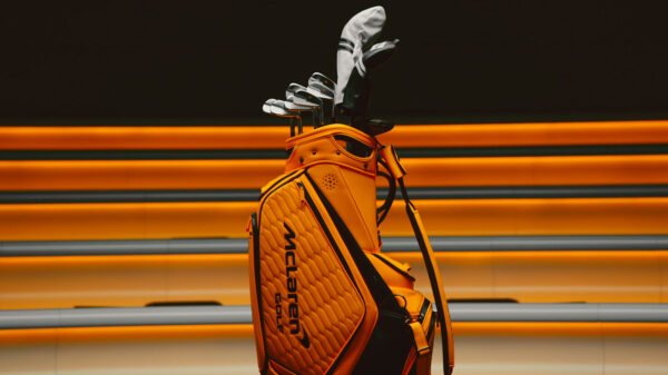 McLaren Golf irons displayed in an orange McLaren-branded golf bag against a racing-inspired backdrop.