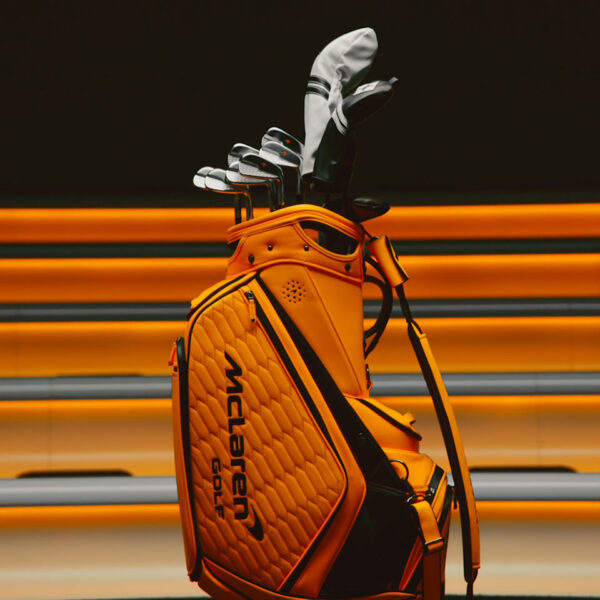 McLaren Golf irons displayed in an orange McLaren-branded golf bag against a racing-inspired backdrop.